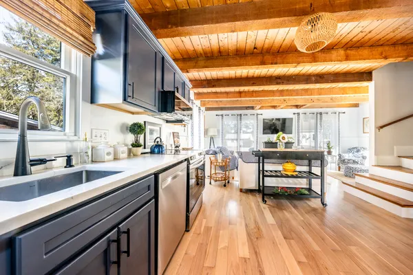 a kitchen with stainless steel appliances kitchen island granite countertop a table chairs and a barbeque