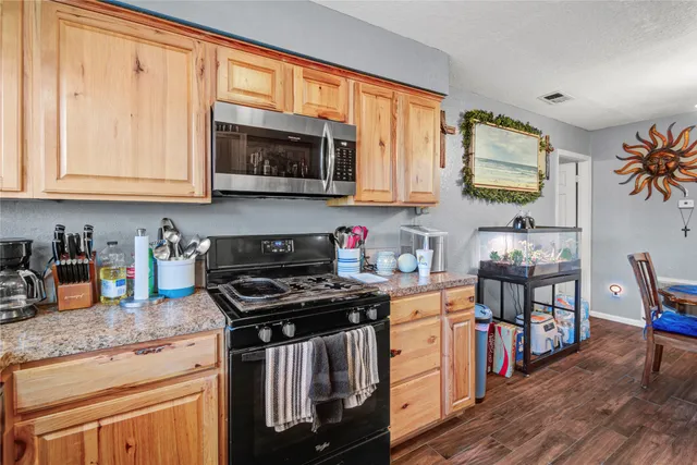 a kitchen with stainless steel appliances granite countertop a stove top oven a sink dishwasher and cabinets with wooden floor