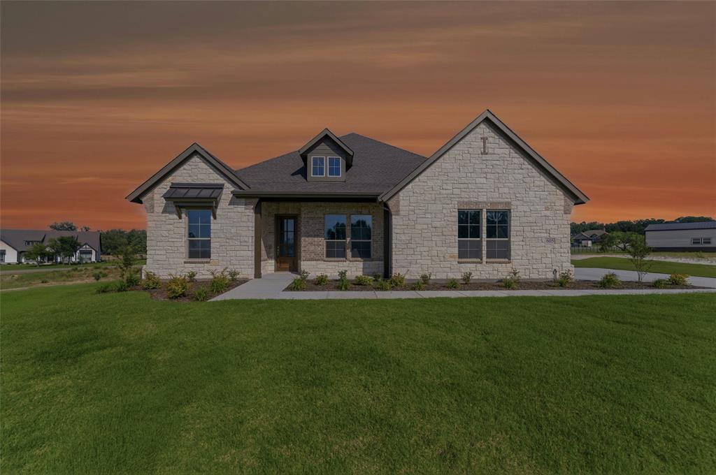 605 Tay Tay Way Springtown, TX 76082 - Photo 31 of 31 Stone facade residence featuring a dark shingle roof, a prominent dormer window, a covered entry, and a window awning
