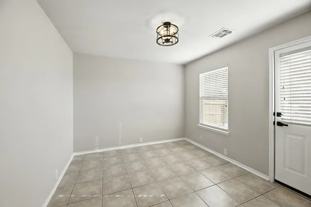 an empty room with windows and chandelier fan