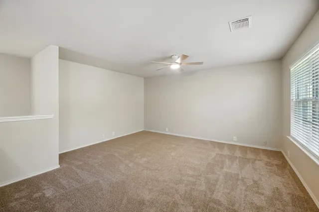 an empty room with chandelier fan and windows