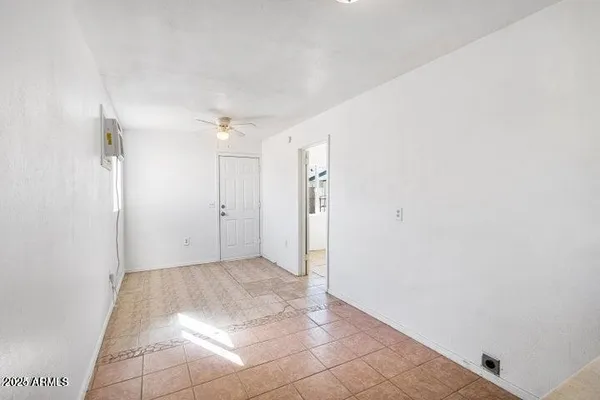 an empty room with a chandelier fan and windows