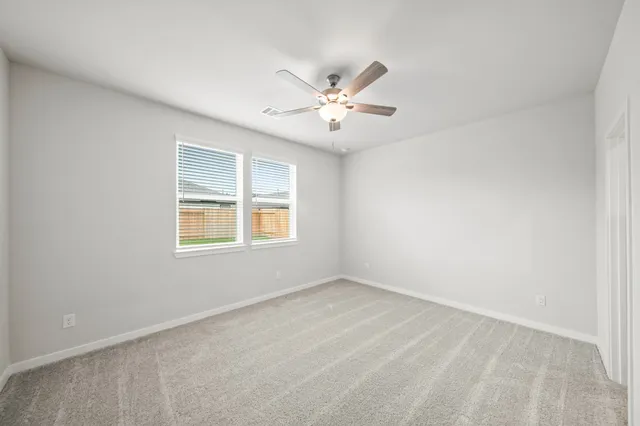 an empty room with a window and a ceiling fan