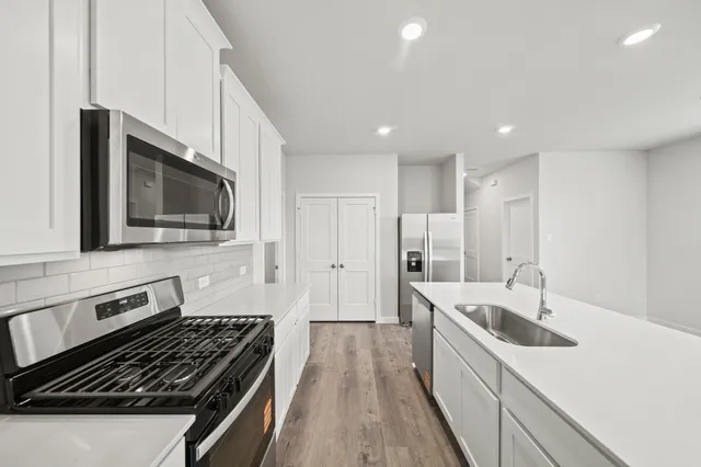a kitchen with stainless steel appliances a sink a stove and a microwave