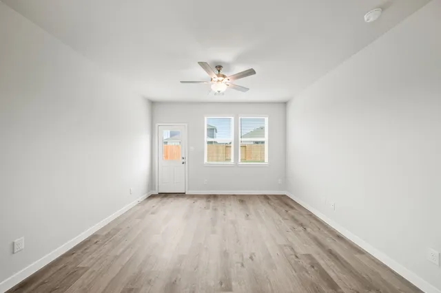 an empty room with a window and a ceiling fan