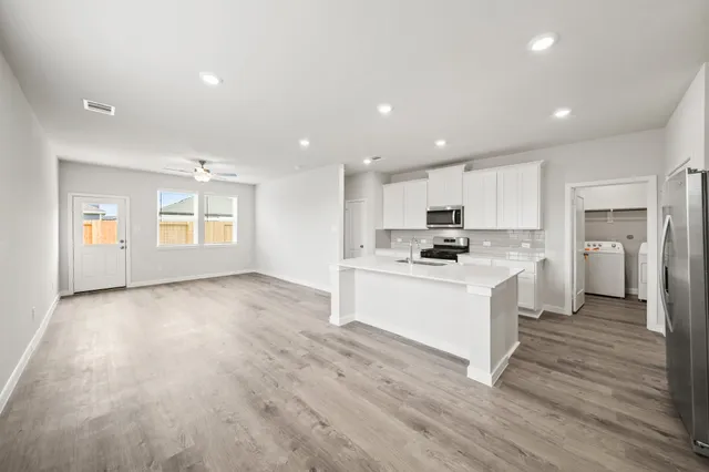 a view of kitchen with granite countertop stainless steel appliances refrigerator sink and cabinets