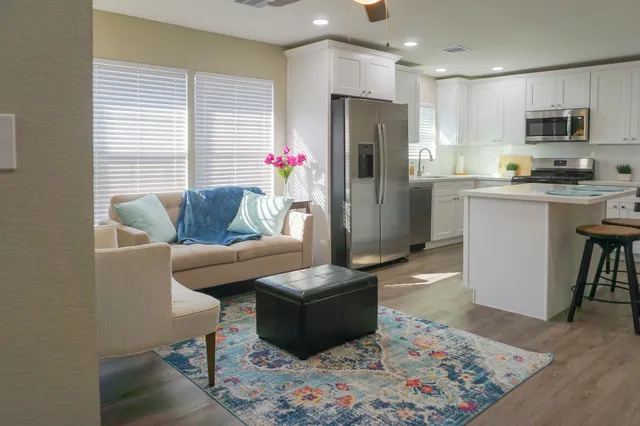 a living room with furniture and a refrigerator