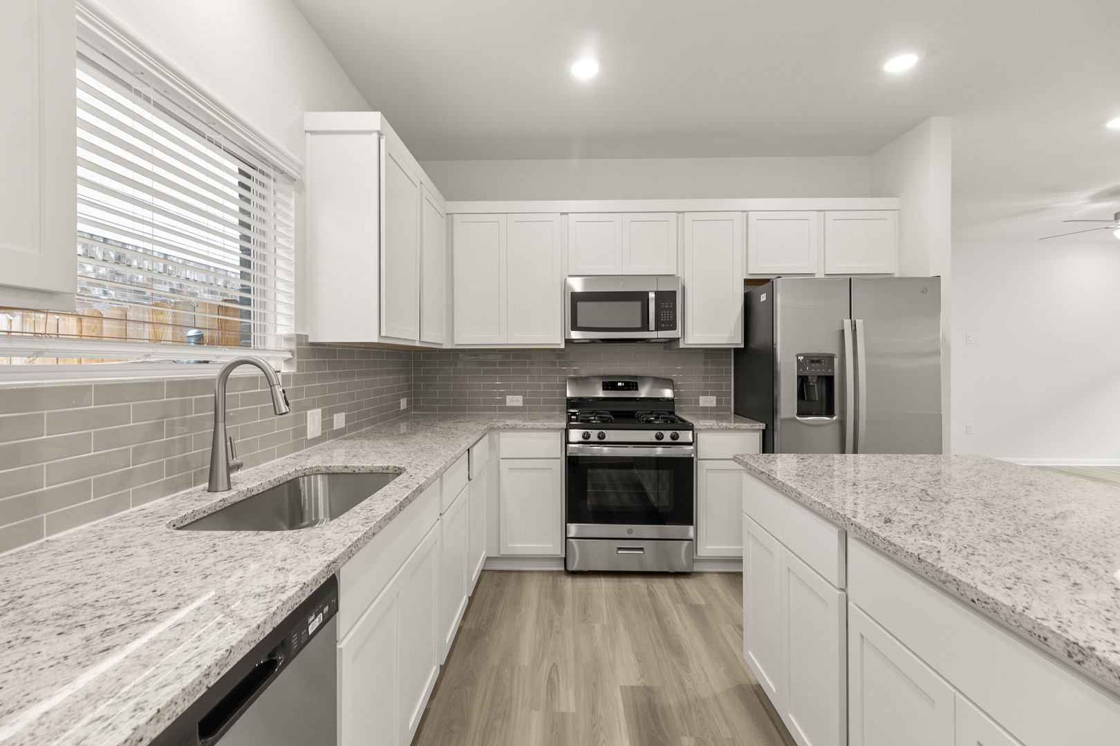 18605 Emu Lane Manor, TX 78653 - Photo 13 of 27 The kitchen features white cabinetry, granite countertops, and stainless steel appliances, including a refrigerator, microwave, and range