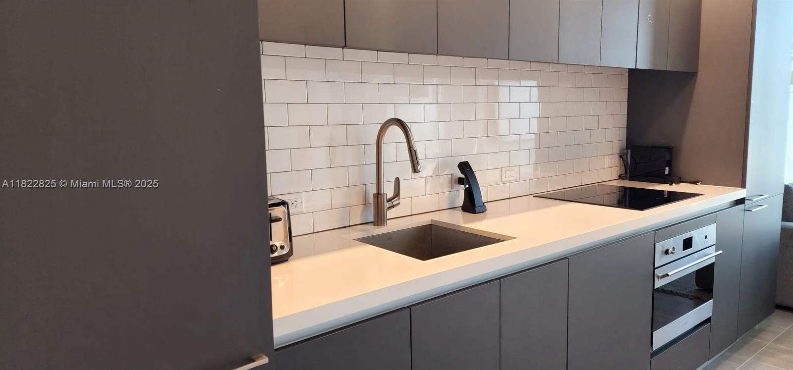 227 Northeast 2nd Street, Unit 2907 Miami, FL 33132 - Photo 4 of 36 a kitchen with a sink and a stove with wooden floor