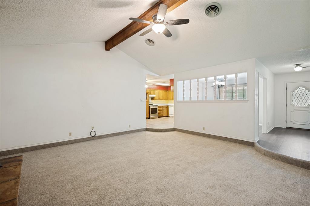 508 South Pedigo Street Pilot Point, TX 76258 - Photo 4 of 26 Spacious living area featuring vaulted ceilings with exposed wood beams, a ceiling fan, and light-toned carpeting