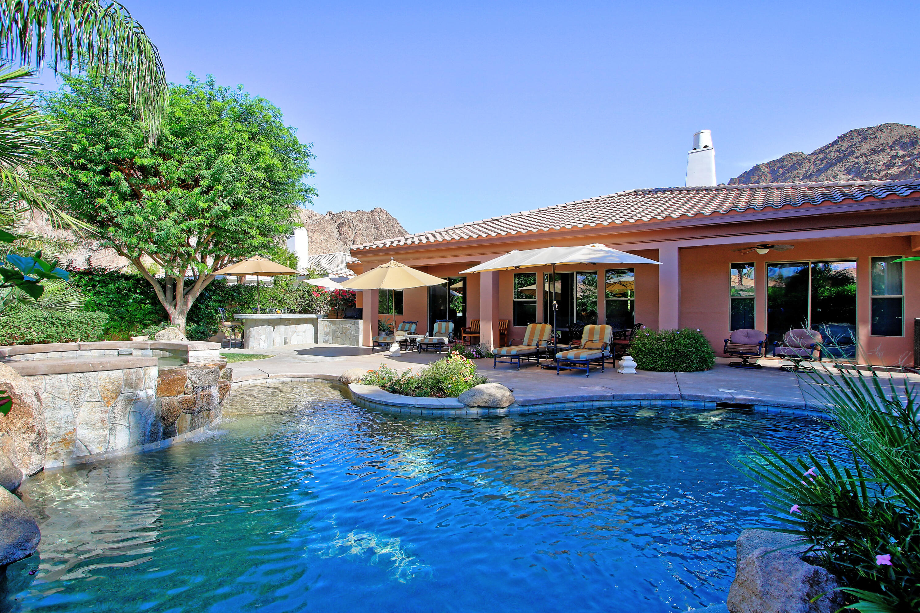 a view of a house with patio chairs and swimming pool