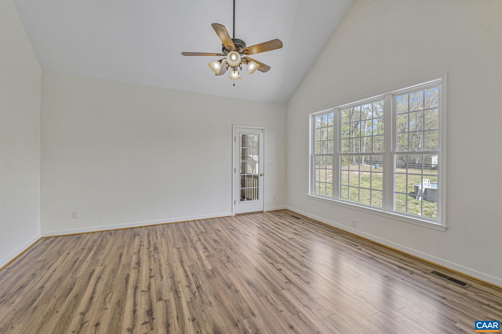 1130 Race Ground Road Rochelle, VA 22738 - Photo 18 of 58 an empty room with wooden floor chandelier fan and windows