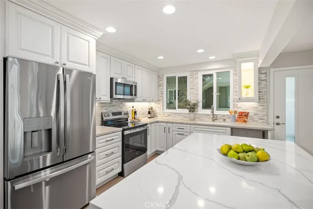 a kitchen with stainless steel appliances a refrigerator a sink a stove and cabinets