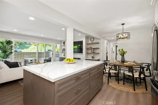 a view of kitchen island with stainless steel appliances granite countertop dining room and windows