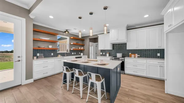 a kitchen with stainless steel appliances kitchen island granite countertop a table chairs sink and cabinets