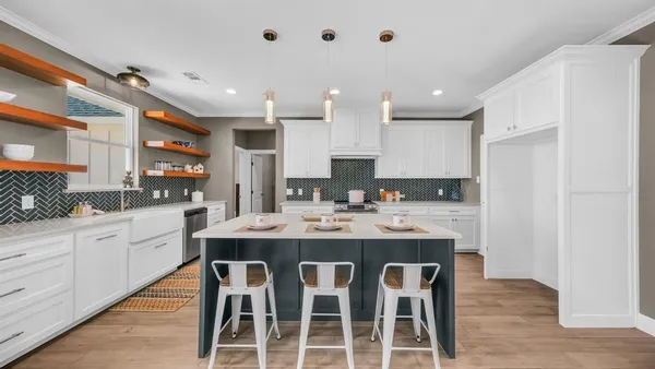 a kitchen with kitchen island granite countertop a sink and white cabinets