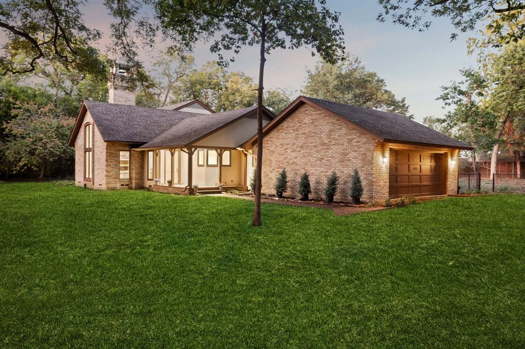 a view of a house with a big yard potted plants and large tree