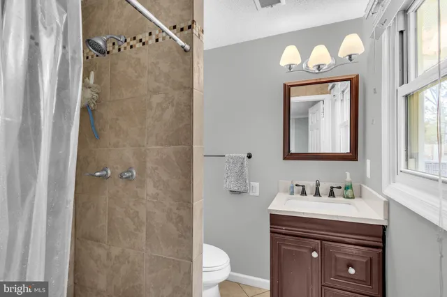 a bathroom with a granite countertop sink a toilet and a mirror