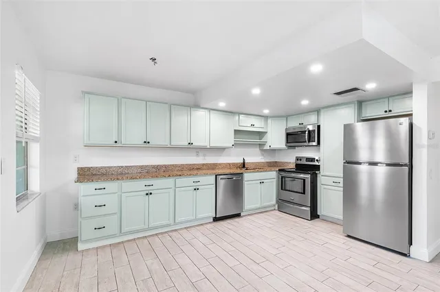 a kitchen with granite countertop a refrigerator stove top oven and sink