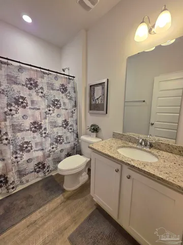 a bathroom with a granite countertop toilet sink mirror and shower