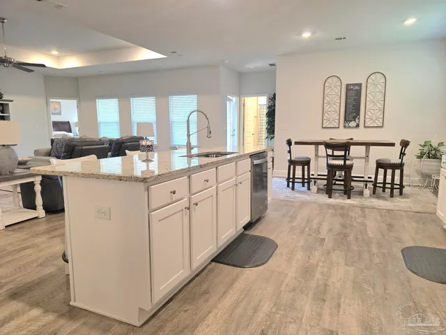 a kitchen with stainless steel appliances granite countertop a stove top oven a sink a dining table and chairs with wooden floor