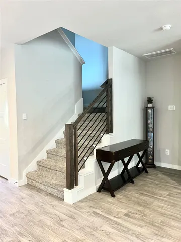 a view of an empty room with stairs wooden floor and with furniture