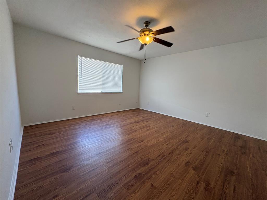 7226 Little Canyon Road Dallas, TX 75249 - Photo 17 of 30 a view of an empty room with wooden floor and a window