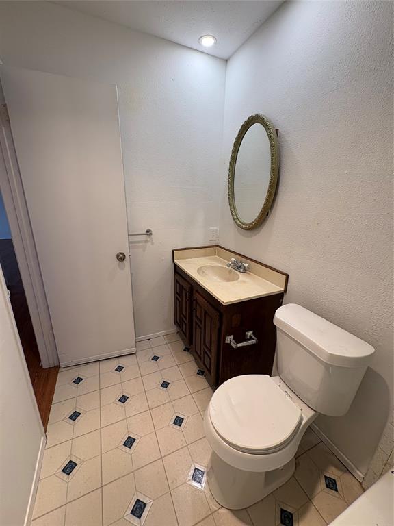 7226 Little Canyon Road Dallas, TX 75249 - Photo 26 of 30 a bathroom with a toilet a sink a mirror and vanity