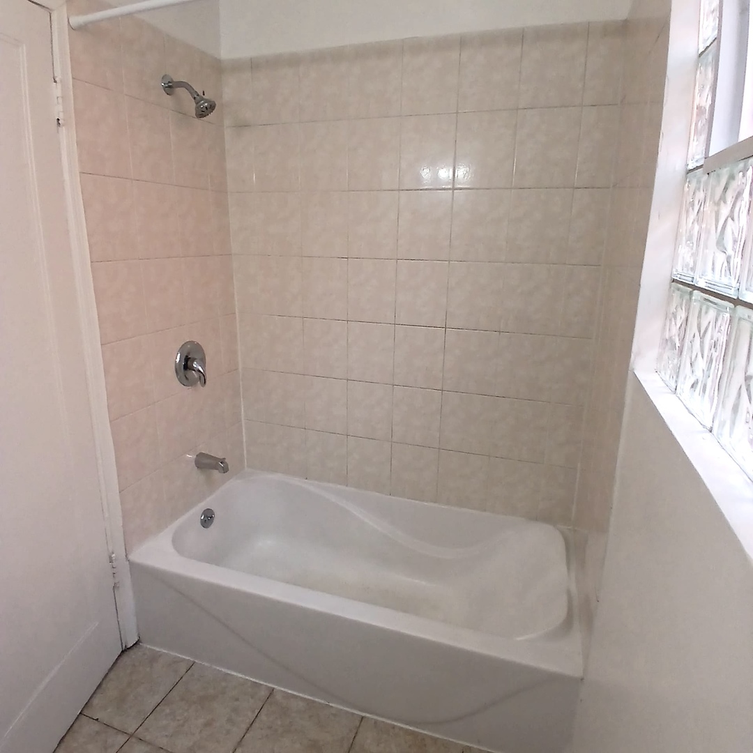 4808 West Barry Avenue, Unit 2W Chicago, IL 60641 - Photo 11 of 11 a white bath tub and shower in a bathroom