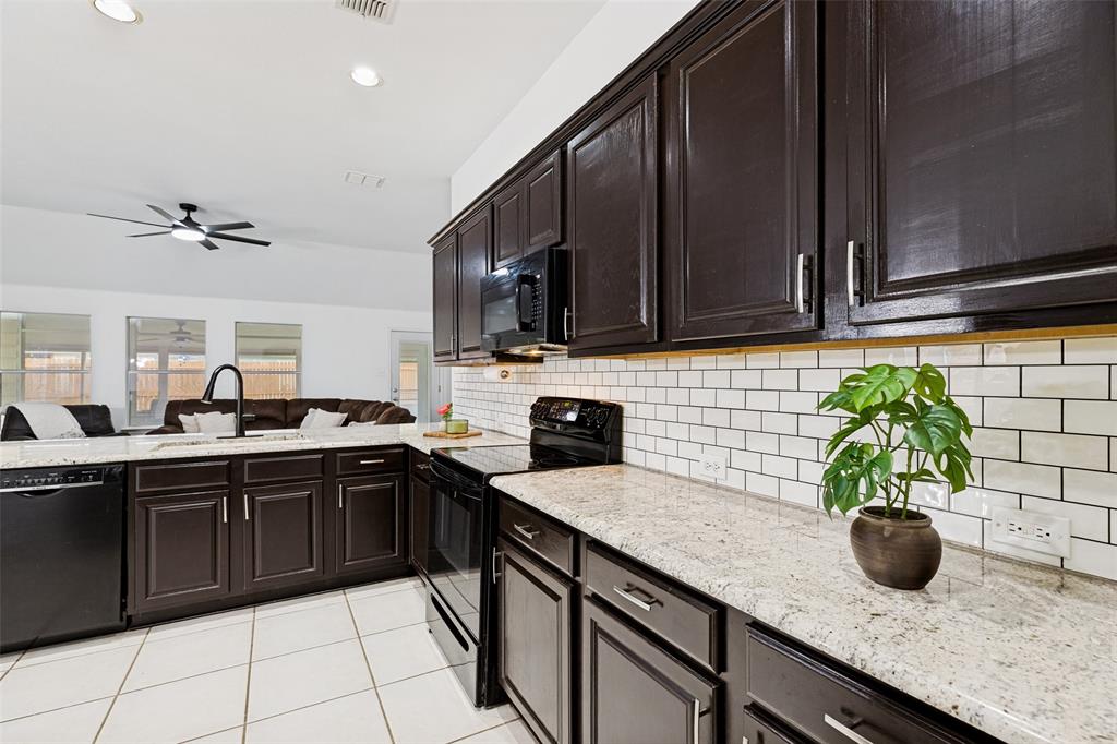 4305 Ridgewood Road Melissa, TX 75454 - Photo 9 of 26 Kitchen featuring dark cabinetry with brushed nickel hardware, light granite countertops, white subway tile backsplash, and black appliances