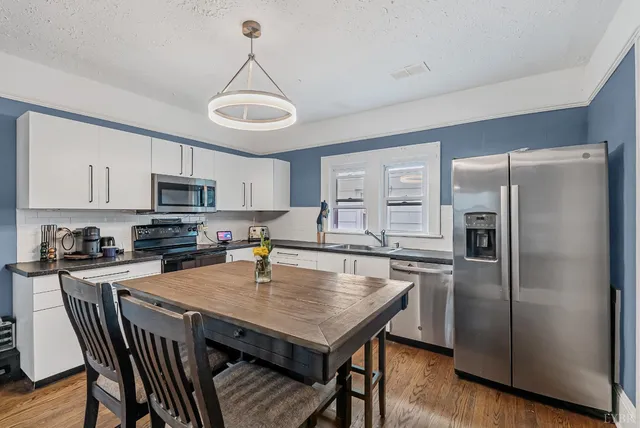 a kitchen with stainless steel appliances granite countertop a refrigerator a stove a sink a microwave and dining table