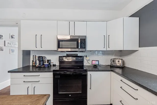 a kitchen with white cabinets and black appliances