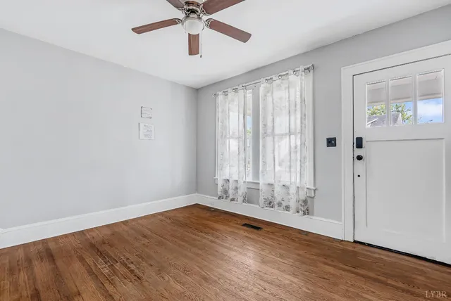 an empty room with wooden floor fan and windows