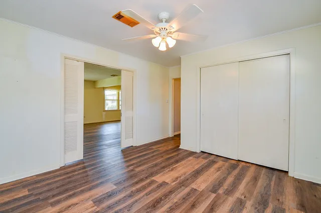 an empty room with wooden floor and a ceiling fan