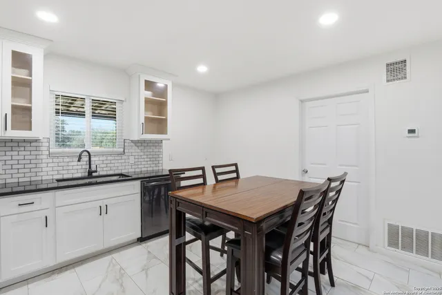 a kitchen with granite countertop a sink and white cabinets