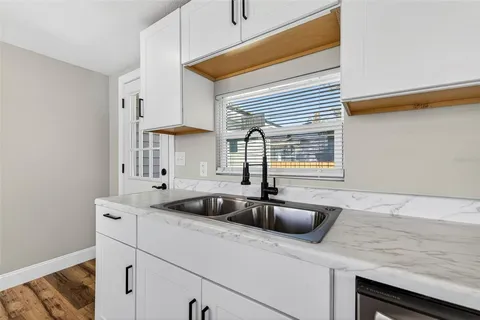 a kitchen with white cabinets stainless steel appliances and a window