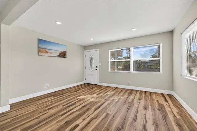 a view of empty room with wooden floor and kitchen