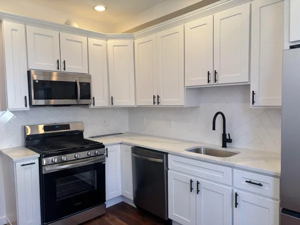 a kitchen with stainless steel appliances granite countertop a stove a microwave a sink and cabinets