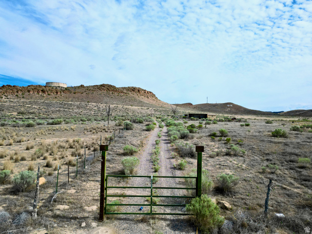 600 East E Street Moroni, UT 84646 - Photo 1 of 38 Gated property entrance with a dirt road extending into the distance, framed by natural desert flora