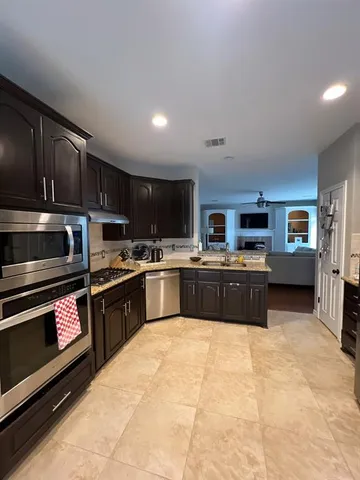 a kitchen with stainless steel appliances kitchen island granite countertop a stove sink and cabinets