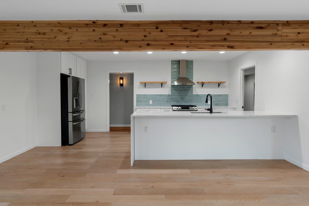 3404 Touchstone Street Austin, TX 78723 - Photo 11 of 32 Kitchen with open shelves, a peninsula, stainless steel appliances, light wood-style floors, and white cabinets