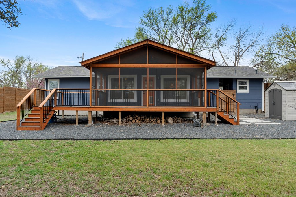 3404 Touchstone Street Austin, TX 78723 - Photo 26 of 32 Rear view of property featuring a wooden deck, a sunroom, a storage unit, a lawn, and a shingled roof