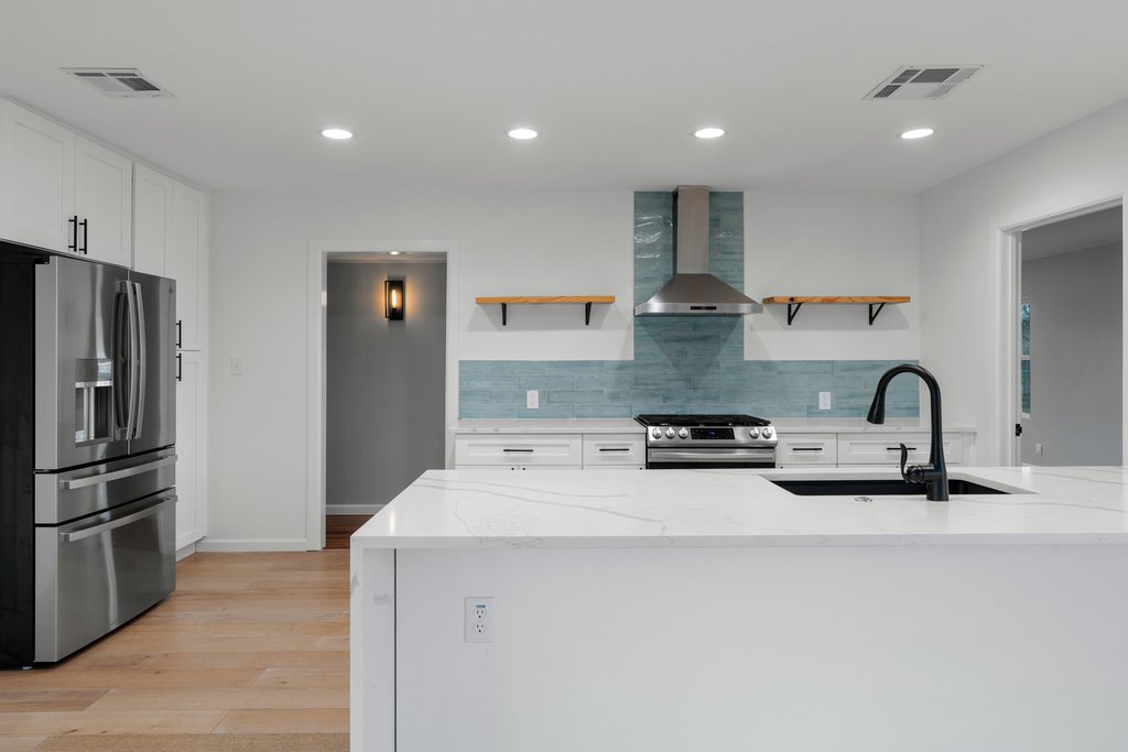 3404 Touchstone Street Austin, TX 78723 - Photo 9 of 32 Kitchen with stainless steel appliances, light stone counters, light wood-type flooring, open shelves, and backsplash