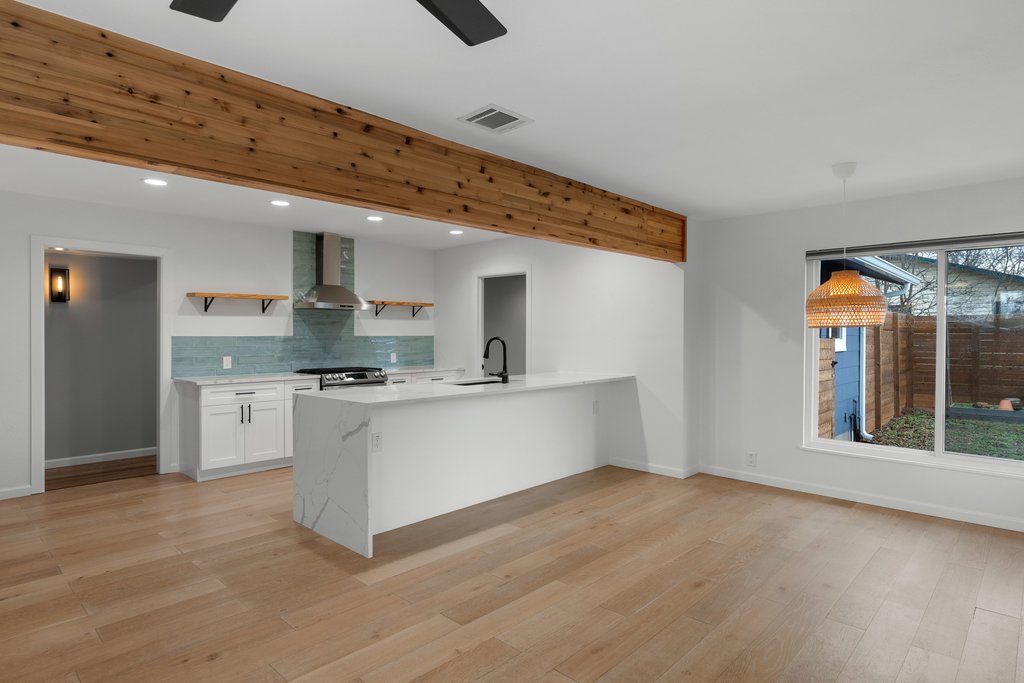 3404 Touchstone Street Austin, TX 78723 - Photo 10 of 32 Kitchen featuring open shelves, white cabinets, a peninsula, light stone counters, and light wood-style floors