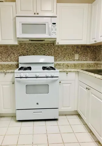 a kitchen with white cabinets and white appliances