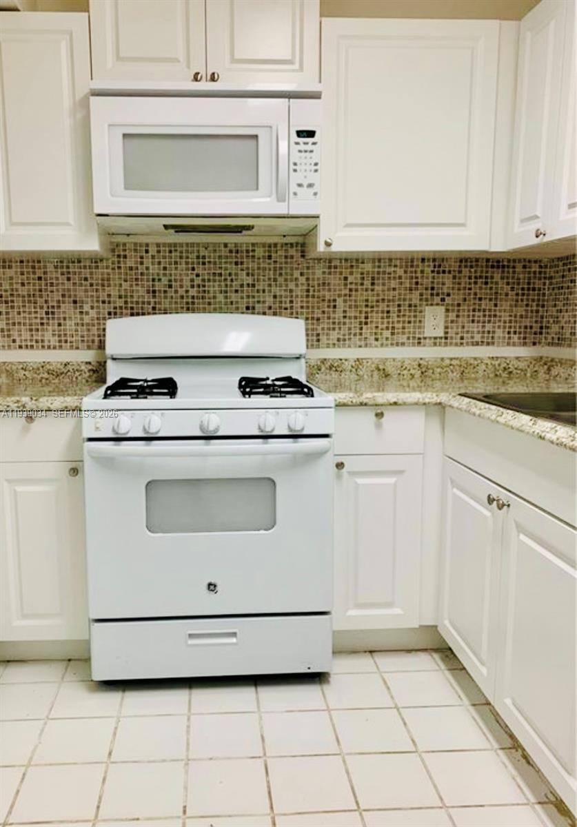 15340 Southwest 106th Terrace, Unit 819 Miami, FL 33196 - Photo 4 of 16 a kitchen with white cabinets and white appliances