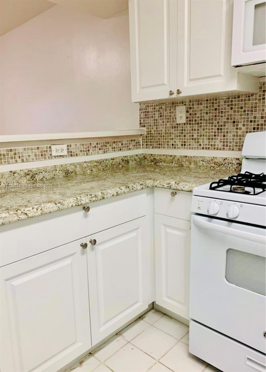 15340 Southwest 106th Terrace, Unit 819 Miami, FL 33196 - Photo 5 of 16 a kitchen with granite countertop white cabinets and white appliances
