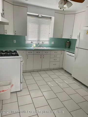 a kitchen with a sink a stove cabinets and a window