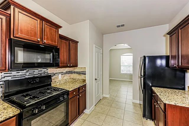 a kitchen with granite countertop a stove and a microwave