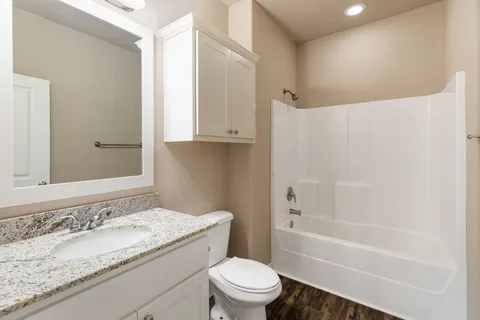 a bathroom with a granite countertop sink toilet and shower